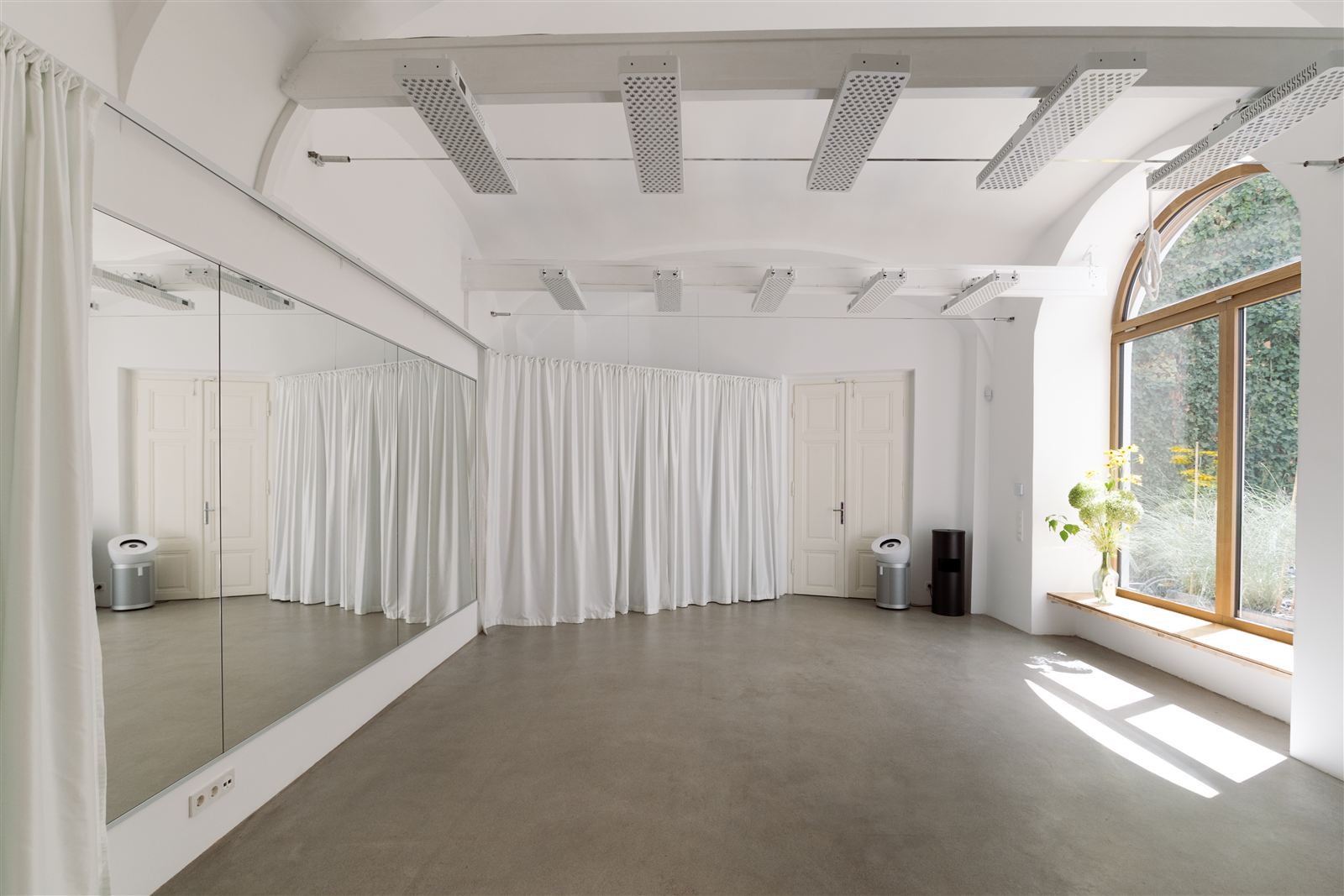 Wide view of the studio room with mirrored wall and arched window